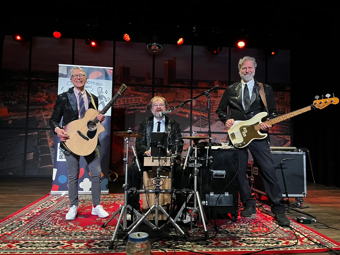 The three members of OK Boomer Band with guitar, drums, and bass onstage in the band’s official electronic press-kit photo.